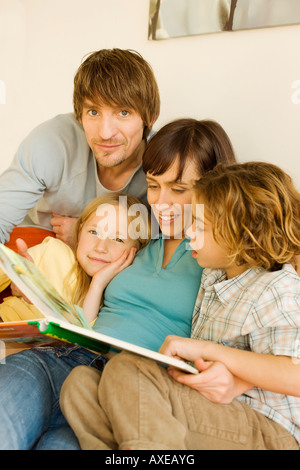 Family reading story book in living room Stock Photo