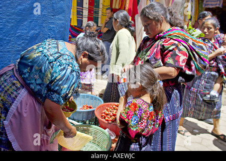 GUATEMALA CHICHICASTENANGO Local Quiche mother and daughter in traditional dress buying strawberries from a market vendor Stock Photo