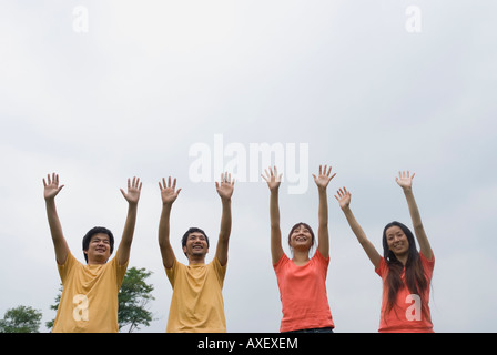 Four people standing with arms raised Stock Photo