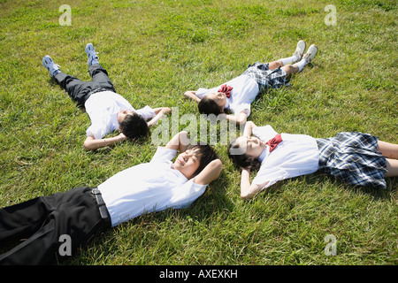 School children sleeping in grass field Stock Photo