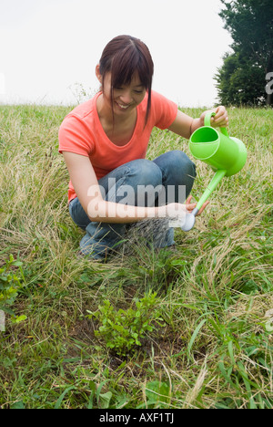 Young woman watering tree Stock Photo