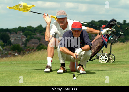 Senior Golfer with Caddie giving advice on a green on Andover Golf Course Hampshire England UK Europe Stock Photo