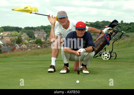 Senior Golfers with Caddy giving advice on the green Stock Photo