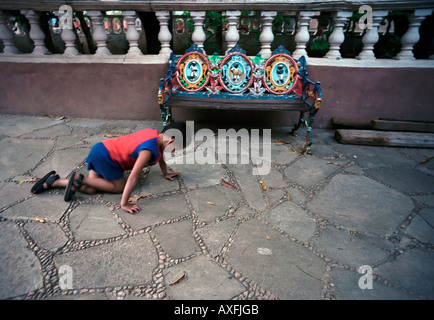 A young boy plays hide and seek near an ornate bench in a square of Batopilas Stock Photo