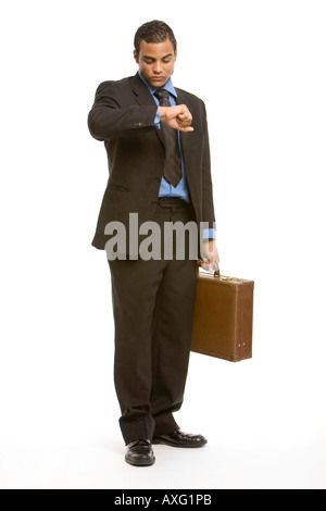 Young executive wearing a suit and carrying a brief case checking his watch with some impatience Stock Photo