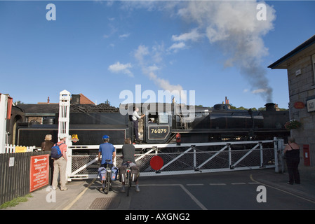 Steam train pulling out of station on level crossing on North Yorkshire Moors Railway Grosmont North Yorkshire England Stock Photo