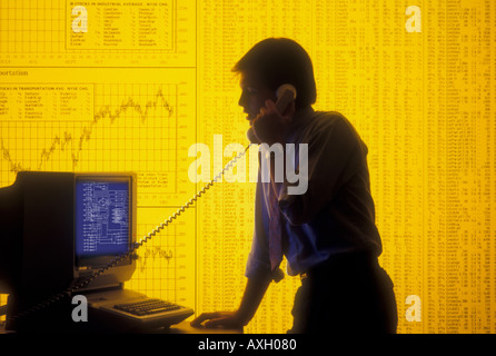 computer operator studying financial statistics on monitor with telephone in business environment Stock Photo