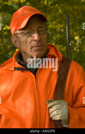 PORTRAIT OF DEER HUNTER IN BLAZE ORANGE AND RIFLE OVER SHOULDER NORTH CENTRAL MINNESOTA Stock Photo