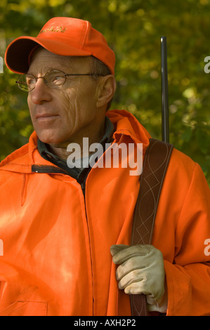 PORTRAIT OF DEER HUNTER IN BLAZE ORANGE AND RIFLE OVER SHOULDER NORTH CENTRAL MINNESOTA Stock Photo