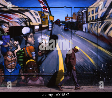 Elderly man walks, head bowed, past a mural in Notting Hill, London, England. Stock Photo
