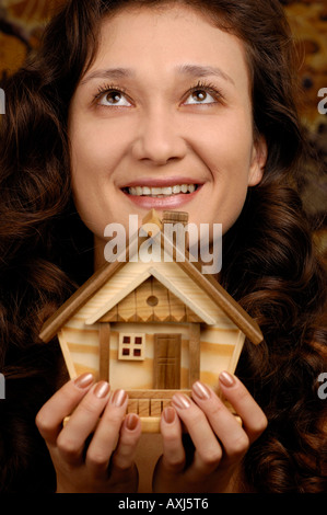 Happy smiling woman holding a small wooden house in her hands Stock Photo