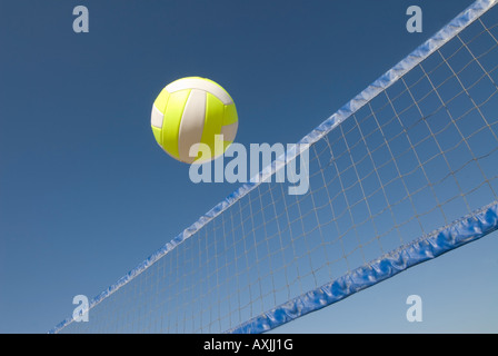 A volleyball player lobs a ball during a game at the beach Stock Photo