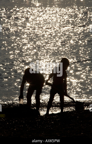 Two young boys children brothers playing in sand on the beach by the sea in Saronida Attica or Atiki Greece NAOH CJWH