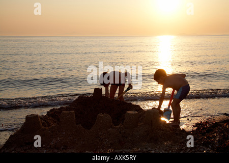 Two young boys children brothers playing building a sand castle on the beach by the sea in Saronida Attica or Atiki Greece NAOH