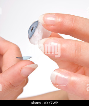 Hands putting a contact lens on a glass eye Stock Photo