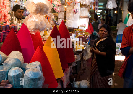 woman shops at the City Market in Bangalore, South India. Piles of coloured powder known as Kum Kum are sold at this stall. Stock Photo