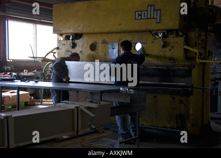 Stock photo of two factory workers operating a hydraulic CNC press brake machine Stock Photo