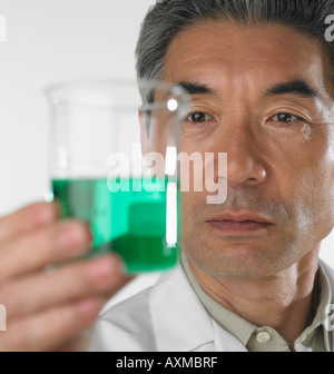 Man looking at beaker of fluid Stock Photo