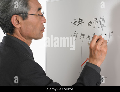 Senior Asian businessman writing on white board Stock Photo