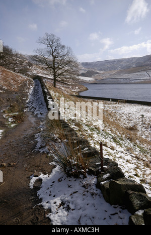 Path around Kinder Reservoir in the snow with view towards Kinder Scout, Peak District, Derbyshire, UK Stock Photo