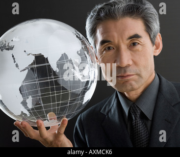 Senior Asian businessman holding clear globe