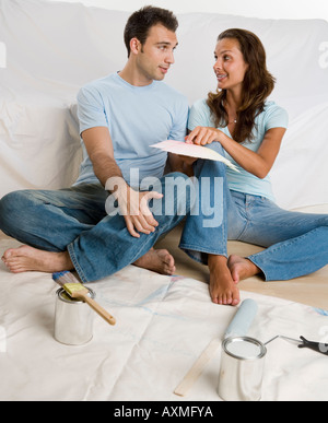 Couple sitting on tarp looking at paint swatches Stock Photo