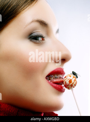 Young woman licking a lollipop on which a fly is sitting. Stock Photo