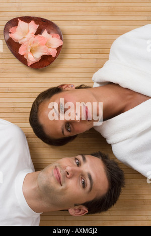 Couple laying on floor next to flowers Stock Photo