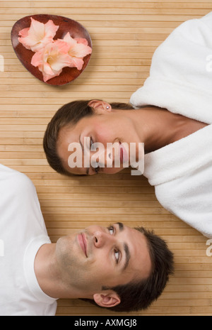 Couple smiling at each other while laying on floor Stock Photo