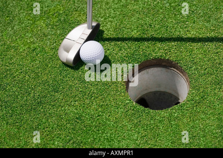 Golf ball near cup on putting green outdoors Stock Photo