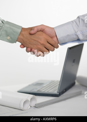 Two men shaking hands over laptop computer Stock Photo