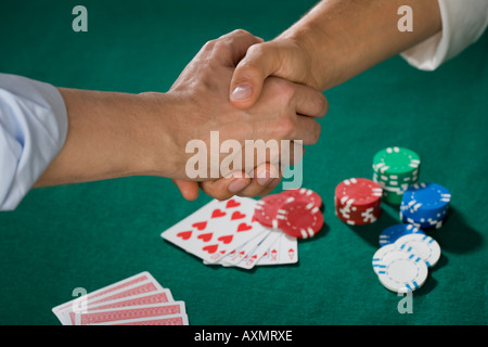 Two men shaking hands over poker game Stock Photo