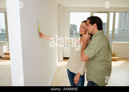 Couple holding paint swatches up to wall Stock Photo