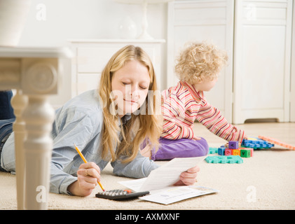 Mother working on calculator while child plays Stock Photo
