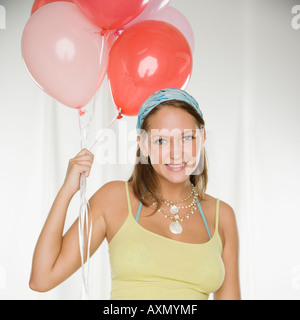 Young woman smiling and holding bunch of balloons Stock Photo