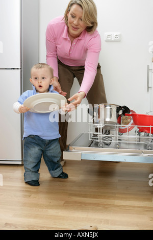 Son and mother emptying a dishwasher Stock Photo