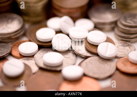 Medicine costs pharmaceutical industry making money pills and coins UK pounds and pence Stock Photo