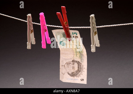 Washed money hanged on a rope currency pegs 5 pounds note dirty money drying Stock Photo