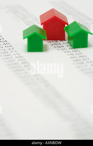 Three plastic miniature-houses standing on a financial paper, selective focus Stock Photo