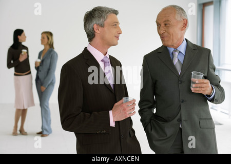 Two managers with glasses in their hands in high spirits, two business women in the background Stock Photo
