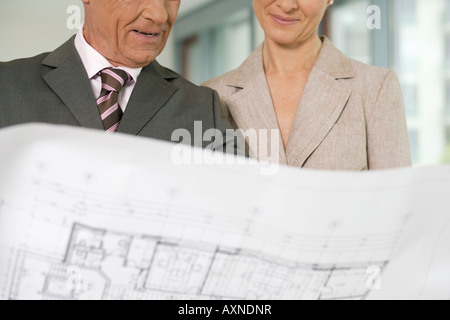 Elderly manager and business woman examining architect's plan Stock Photo