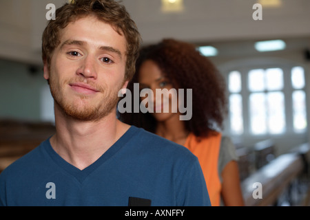 Young man standing in front of an Afro-American woman, both in an auditory, selective focus Stock Photo