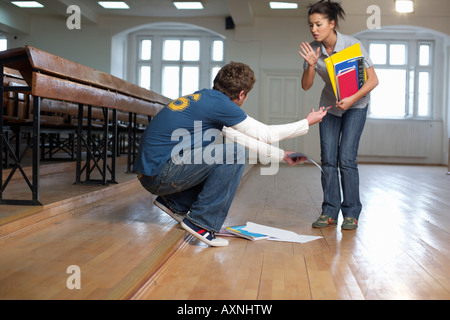 Man picking up the booklets of a young woman in an auditory, low angle view Stock Photo