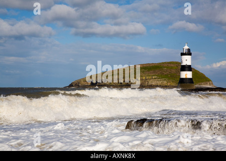 Rough sea in windy weather with Penmon lighthouse (Trwyn Du) and waves in foreground on rocky coast with Puffin Island. Penmon Point Anglesey Wales UK Stock Photo