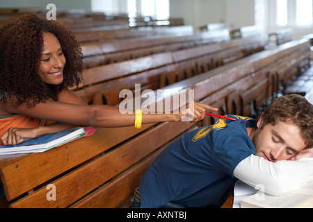 Afro-American woman is trying to annoy a young man who is sleeping in an auditory, selective focus Stock Photo