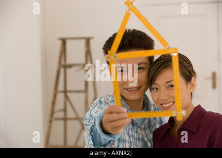 Asian couple with folding ruler shaped like house Stock Photo