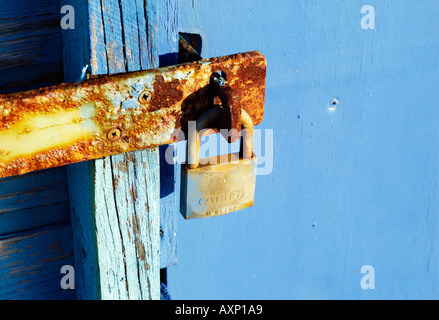 A padlock on the end of a rusty metal used to lock up a beach hut Stock Photo