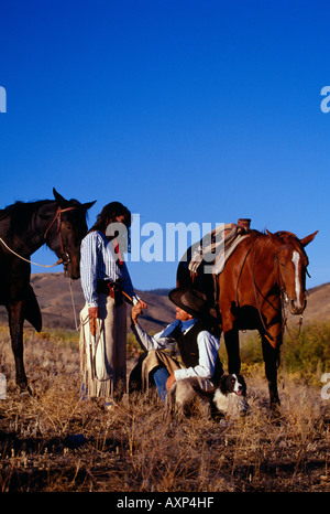 Cowboy and cowgirl holding hands beside their resting horses Ponderosa Ranch Stock Photo