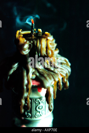 Close up of a smoldering smoking candle with trickles of melted wax Stock Photo