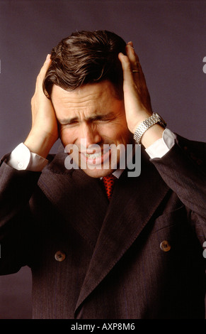 Studio head and shoulders shot of stressed businessman with head in hands Stock Photo